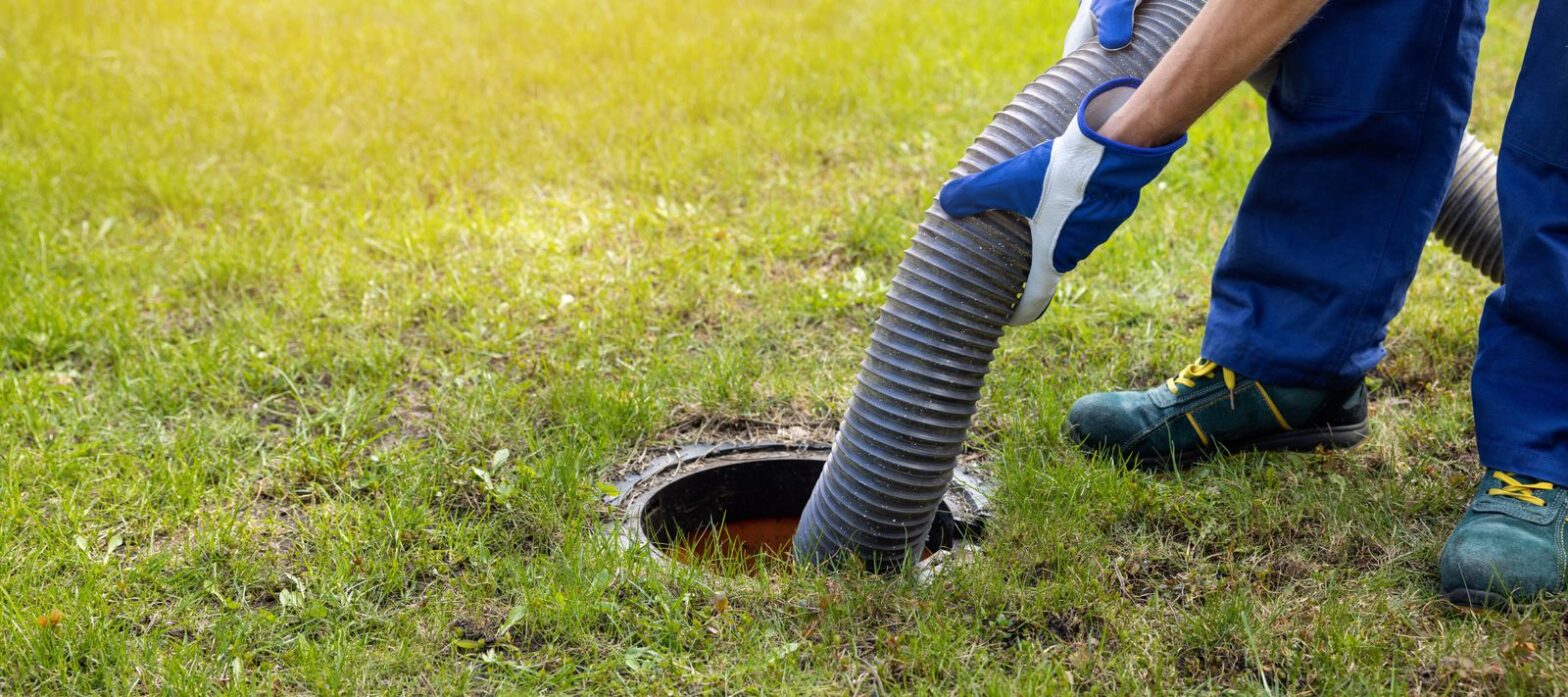 Septic service technician pumping a septic tank in a yard