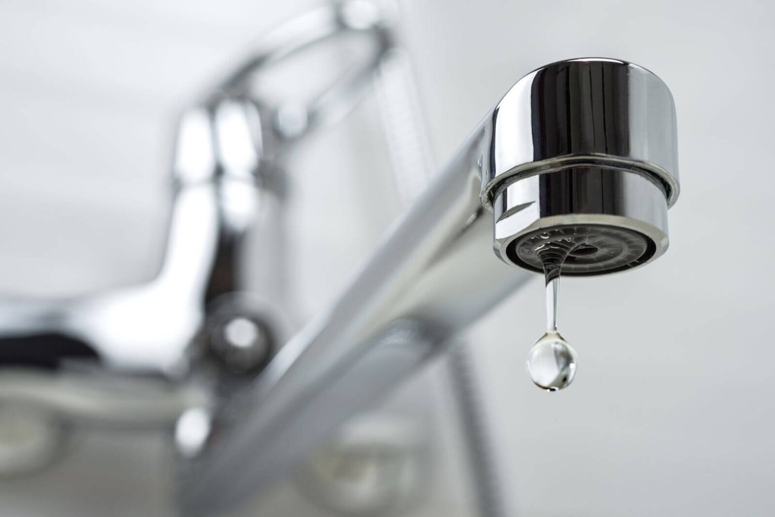 Close-up of a leaking faucet with a water droplet