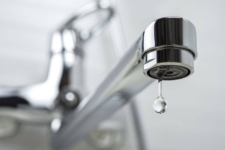 Close-up of a leaking faucet with a water droplet